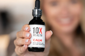 Person holding a bottle of 10X Health Calm supplement with a dropper, smiling in the blurred background.