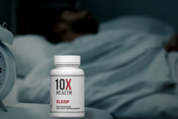 10X Health Sleep supplement bottle in focus on a bedside table with an alarm clock and a blurred background of a person sleeping peacefully in bed.