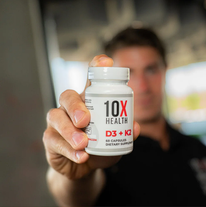 Person holding a bottle of 10X Health D3 + K2 supplement close to the camera.