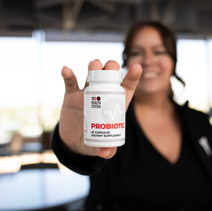 Smiling woman holding a bottle of 10X Health Probiotic.